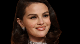 Selena Gomez showing off her red lovergirl nails in a classic almond shape with radiant shine and undeniable romance.