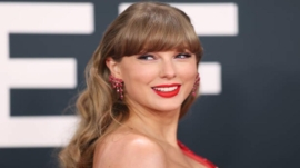 Taylor Swift wearing orange lipstick on Travis Kelce’s podcast.