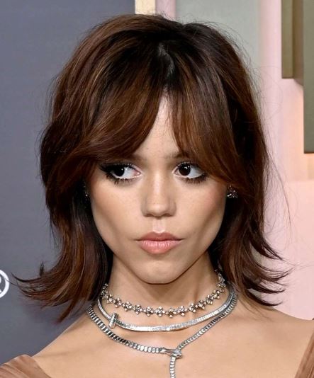 25 Iconic Celebrity Curtain Bangs Styles That Always Look Amazing 9 Jenna Ortega wearing curtain bangs. Her hairstyle features choppy, textured, and slightly piecey curtain bangs