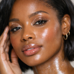 Black American woman showcasing the 2025 glass eye look with glossy eyelids, dewy skin, and natural highlighter in a professional beauty photo.