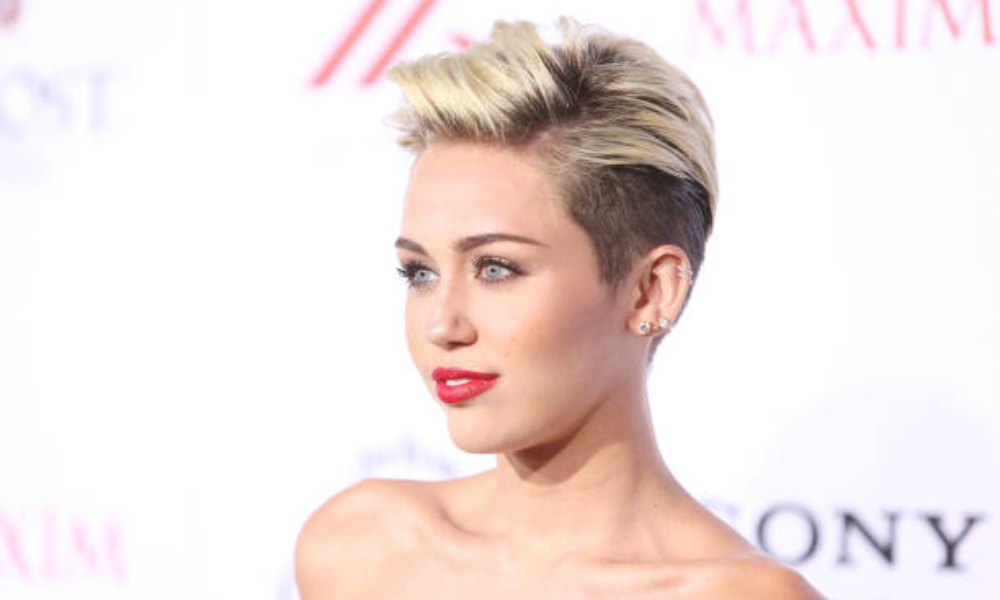 Miley Cyrus Hannah Montana style throwback outfit with blonde hair and gold chain accessories