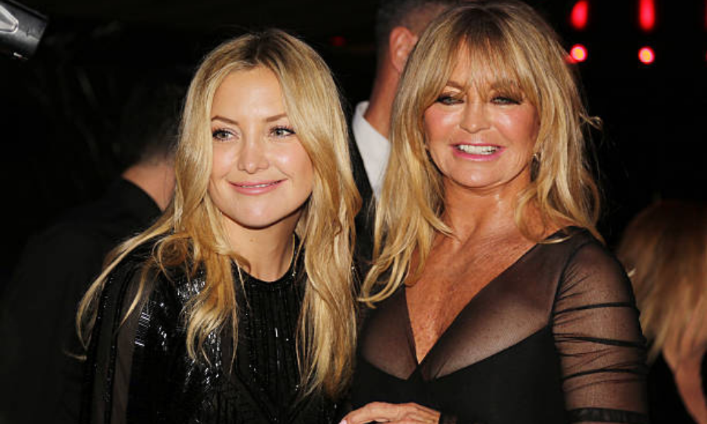 Kate Hudson and Goldie Hawn posing together with matching blonde lobs, glowing skin, and natural glam makeup at a Los Angeles event